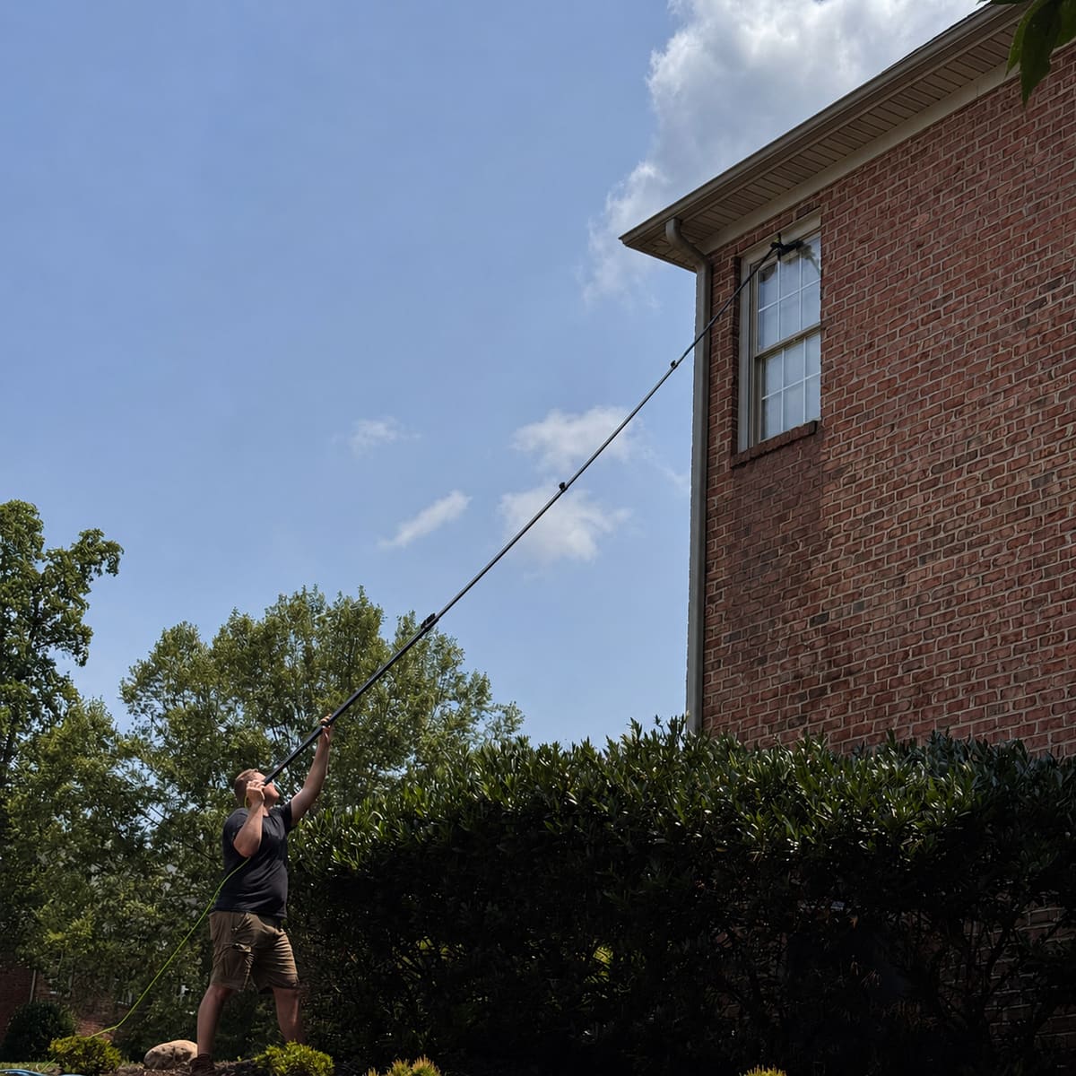 Water-fed pole reaching a second-story window on a brick Lynchburg area home